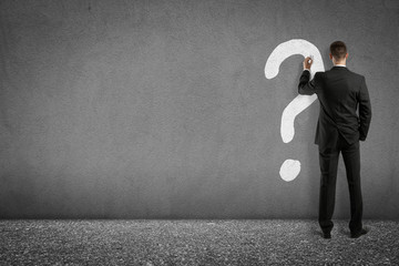 businessman painting question mark on wall