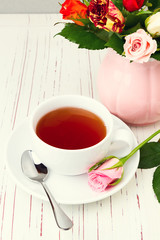 Fototapeta na wymiar Cup of tea on wooden table with rose flowers