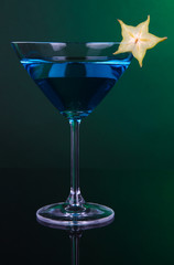 Blue cocktail in martini glass on dark green background