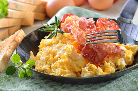 R&uuml;hreier mit gebratenem Speck in der Pfanne