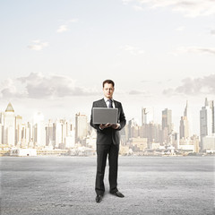 businessman with laptop and city on background