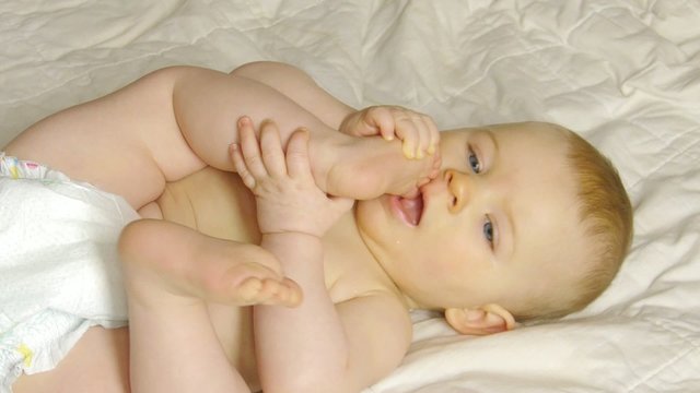 HD1080p Baby laying on a blanket puts her foot in her mouth