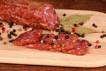 Tasty sausage on chopping board on browm background