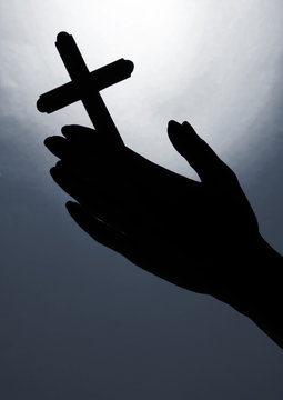 Female hands with crucifix, on bright grey background