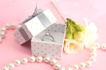 Beautiful box with wedding ring and flower on pink background