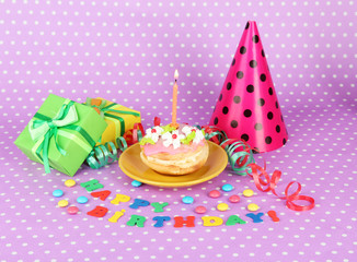 Colorful birthday cake with candle and gifts on pink background