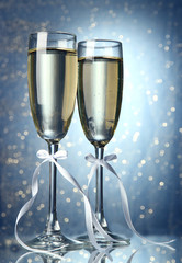 Two glasses of champagne on bright background with lights