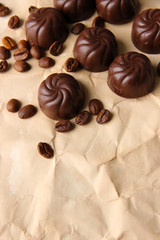 Chocolate candies and coffee beans, on beige paper background