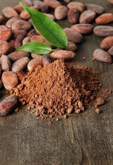 Cocoa beans and cocoa powder on wooden background