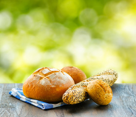 Fresh bread and checkered napkin on wooden table on rural backgr