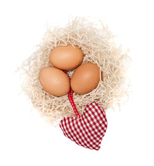 Brown eggs in a nest, decorated with the checkered red heart
