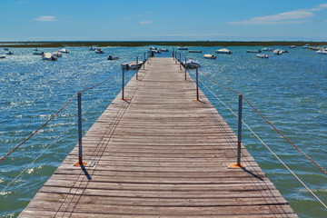 Wooden bridge in the port at sea against the boats.