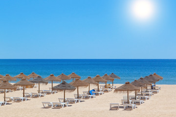 Seascape beach umbrellas and deck chairs on the background of th