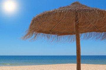 Wooden straw umbrella for the sun on the beach near the sea.