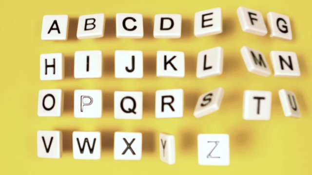 Plastic letters bouncing and showing alphabet on yellow surface