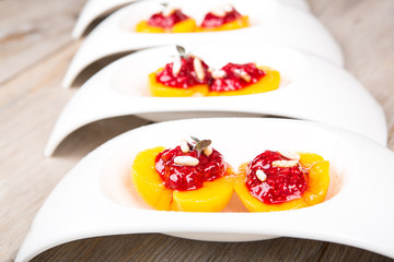 Sweet dessert with peaches filled with raspberry puree