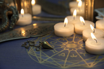 Astrologischer Kreis im Kerzenschein mit Pendel und Spiegel