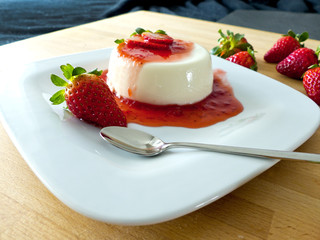 Panna Cotta auf einem Teller und Holzbrett