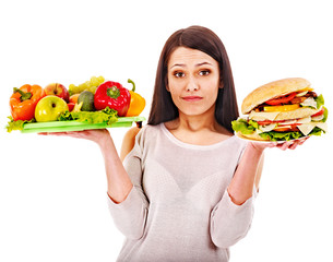 Woman choosing between fruit and hamburger.