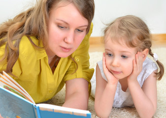 Young woman and little girl read a book