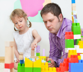 Father and daughter playing with coloured blocks.