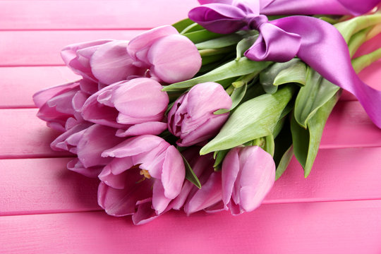 Fototapeta Beautiful bouquet of purple tulips on pink wooden background