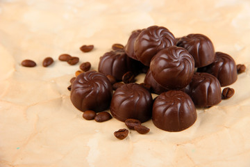 Chocolate candies and coffee beans, on beige paper background