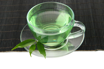 Transparent cup of green tea on bamboo mat, isolated on white