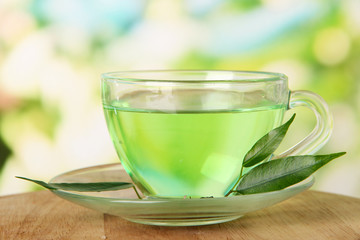 Transparent cup of green tea, on nature background