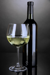 White wine glass and bottle of wine on grey background