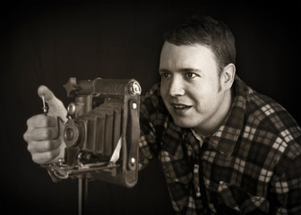 smiling photographer using vintage folding lens camera