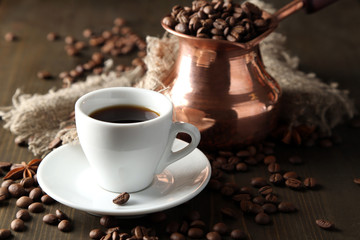 Cup of coffee and pot on wooden background