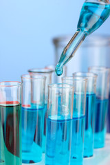 Laboratory pipette with drop of color liquid over glass test