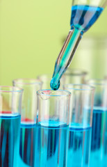 Laboratory pipette with drop of color liquid over glass test