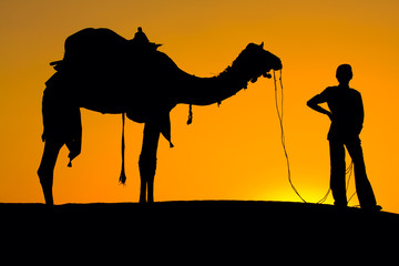 Silhouette of a man and camel at sunset, India