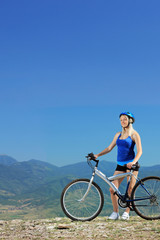 A young female biker posing with a mountain bike