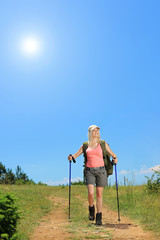 Young woman with backpack walking at sunny day in the mountain