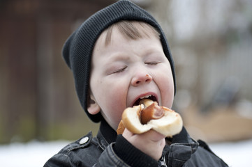 Young boy eating hotdog