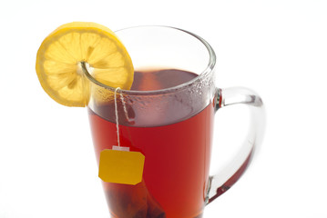 Tea with lemon in a glass cup on a white background. Tea bag