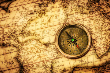 Plakat Vintage Kompas leży na starożytnej mapie świata.