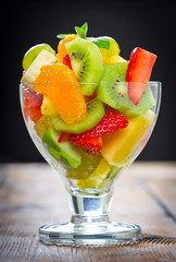 Fruit salad in the glass on the wooden table
