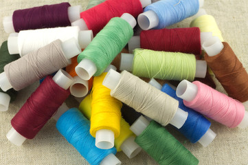 Lot of color thread spools on beige fabric close up