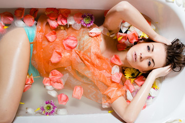 Beautiful lady taking a bath with flower petals