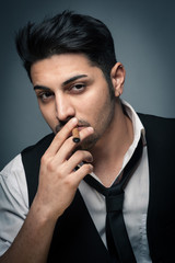 Young man close up portrait with cigar against grey background.