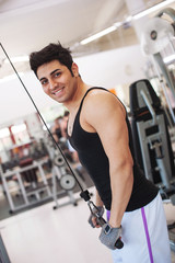 Young smiling man training in the gym.
