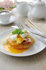 Boiled eggs (poached) with ham on a bun with sauce