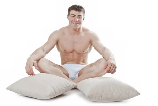 Attractive young man sitting next to the pillows
