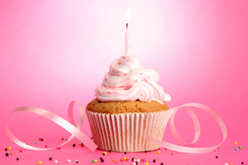 tasty birthday cupcake with candle, on pink background