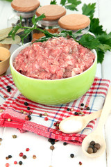 Bowl of raw ground meat with spices on wooden table