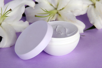 Fototapeta na wymiar Cosmetic cream and beautiful lily, on purple background